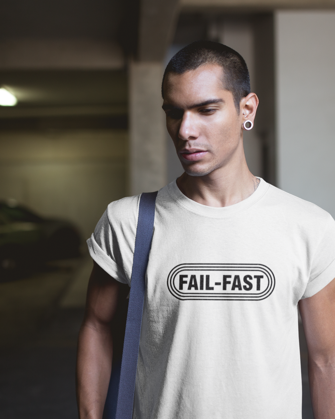hero in white t-shirt featuring a bold retro badge logo with the text “FAIL-FAST.” Industrial design style.