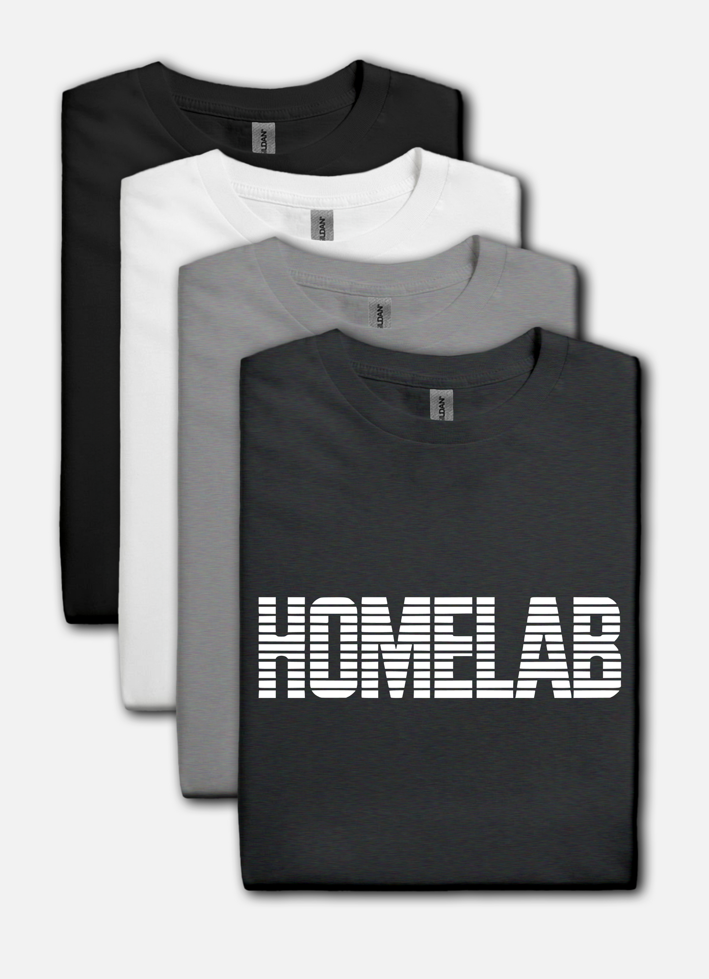 Dark Heather t-shirt laid in a row featuring a bold white “HOMELAB” wordmark with horizontal stripe/scanline effect; retro computer aesthetic with soft natural shadows.