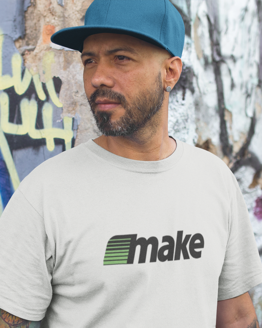 White unisex t-shirt featuring a bold black MAKE wordmark with green speedline motif, inspired by the retro MECC logo behind The Oregon Trail.