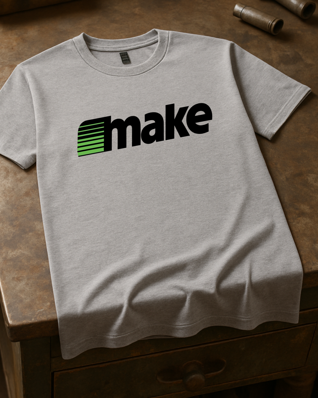 White unisex t-shirt featuring a bold black MAKE wordmark with green speedline motif, inspired by the retro MECC logo behind The Oregon Trail.