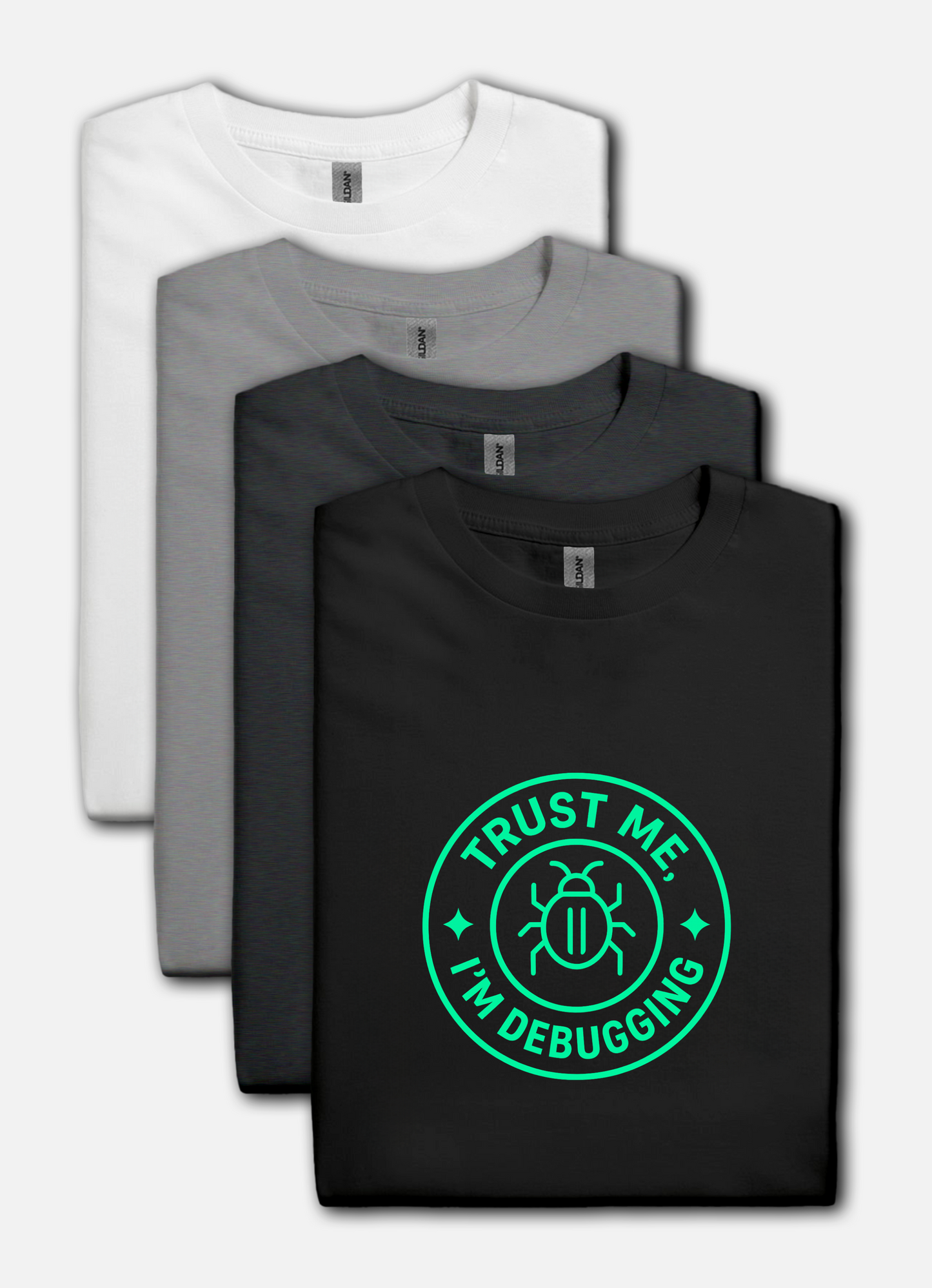 Four folded t-shirts in white, gray, and black with a green 'Trust Me, I'm Debugging' graphic on a white background.