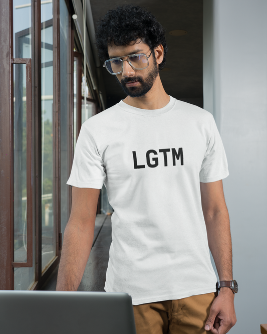 Man wearing a white t-shirt with 'LGTM' text, standing indoors.