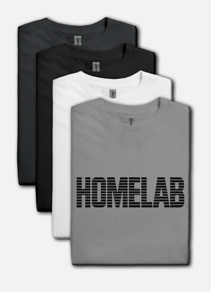 Sport Gray t-shirt laid in a row featuring a bold black “HOMELAB” wordmark with horizontal stripe/scanline effect; retro computer aesthetic with soft natural shadows.